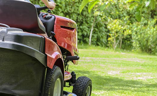 A red ride on mower cutting the grass