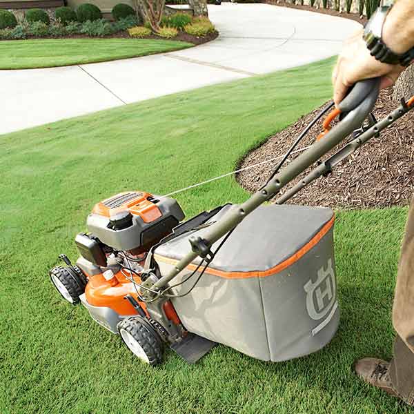 A worker uses a push mower for detailed work