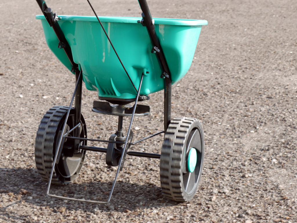 Manually operated seeder filled with grass seeds shot on soil