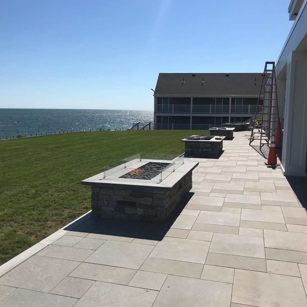 A large patio and several firepits by the green lawn