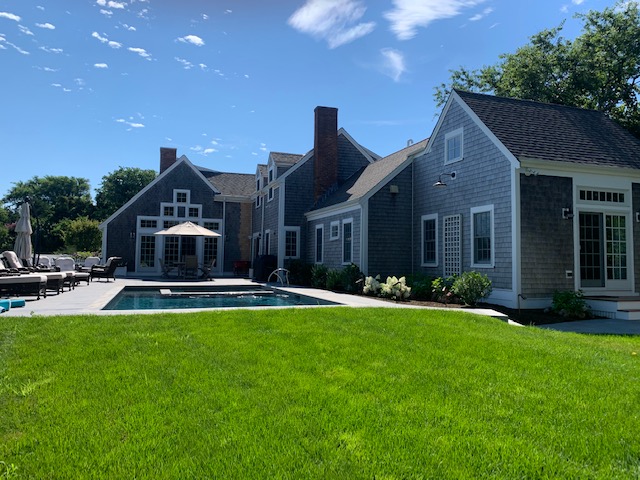 A lush lawn by a pool and large single family residence