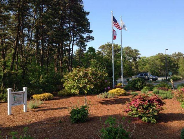 A mulched area outside the Yarmouth Police Department with shrubs and American flag