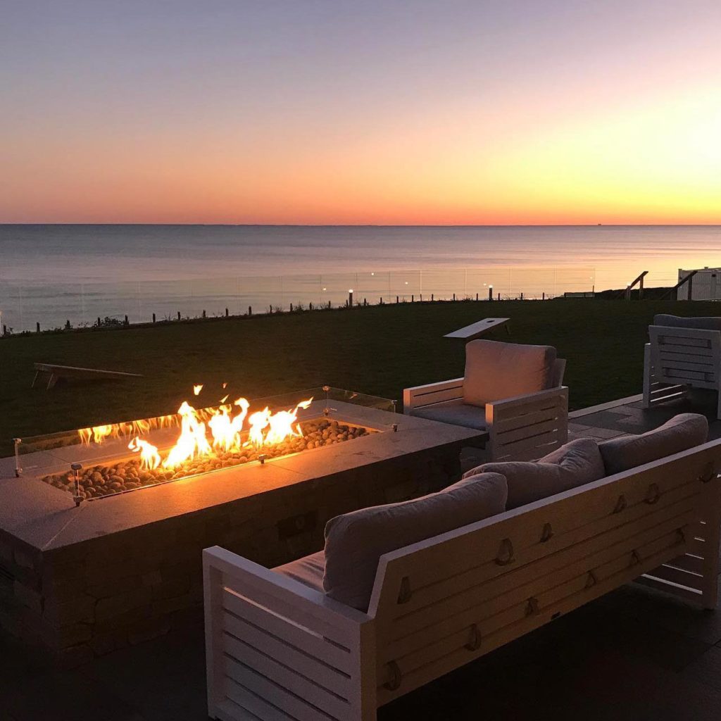 A beautiful sunset over the ocean with a firefit roaring in the foreground