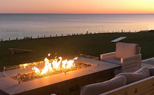 Outdoor gas firepit with an ocean sunset in the background